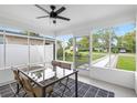 Bright, enclosed porch features a glass dining table, wicker chairs, and tiled floors at 5055 9Th St, Zephyrhills, FL 33542