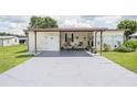 Spacious carport and entrance area with outdoor seating, offering a comfortable and inviting welcome to this cozy home at 5706 Benton St, Zephyrhills, FL 33542