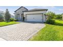 Charming single-story home featuring a stone facade, manicured lawn, and a paved driveway leading to a two-car garage at 6211 Sea Air Dr, Apollo Beach, FL 33572