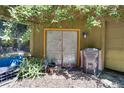 A garage exterior has a door with yellow trim, plants, a window, and trashcans beside the door at 6924 Valrie Ln, Riverview, FL 33569