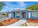 Blue single-story house with arched entryways and a red front door, surrounded by neatly arranged mulch beds at 8033 Norwich Dr, Port Richey, FL 34668