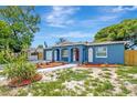 Attractive blue one-story home featuring arched accents, vibrant landscaping, and well-maintained front yard at 8033 Norwich Dr, Port Richey, FL 34668