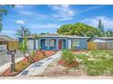 Inviting single-story home with a blue exterior, enhanced by lush landscaping and a charming walkway at 8033 Norwich Dr, Port Richey, FL 34668