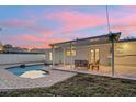 Relaxing covered patio with outdoor furniture overlooking a sparkling pool and landscaped yard at twilight at 1320 Dixie S Ln, St Petersburg, FL 33707