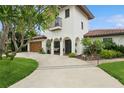 A two-story house showcases a stucco facade, a tiled roof, an arched entry, and tropical landscaping at 1960 Kansas Ne Ave, St Petersburg, FL 33703