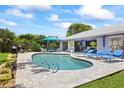 Private backyard oasis featuring a kidney-shaped pool, paver patio, and comfortable lounge furniture at 1983 Seton Dr, Clearwater, FL 33763
