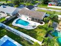 Aerial view of a beautiful backyard featuring a large pool, screened patio, and lush landscaping at 2897 Rosery Ne Rd, Largo, FL 33771