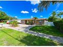 Cozy home featuring a well-maintained lawn, mature trees, and a long driveway at 3303 W Idlewild Ave, Tampa, FL 33614