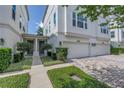 Townhouse exterior with a two-car garage, neatly trimmed shrubs, and a walkway to the entrance, nestled in lush landscaping at 3807 W Cleveland St, Tampa, FL 33609