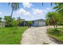 Single-story home with a gray exterior, an attached garage and a large concrete driveway at 4101 Shore Acres Ne Blvd, St Petersburg, FL 33703