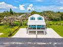 Beautiful home with eye-catching blue accents, a metal roof, and an elevated design situated on a well-maintained lawn at 6679 Wander Ln, New Port Richey, FL 34652