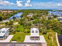 Aerial view of a charming two-story home featuring a metal roof, set amidst a picturesque landscape and beautiful waterfront at 6707 Wander Ln, New Port Richey, FL 34654
