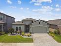 Landscaped home featuring a two-car garage, gray exterior paint, and manicured lawn at 9316 Crescent Ray Dr, Wesley Chapel, FL 33545