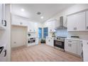 Bright kitchen featuring modern white cabinetry, stainless steel appliances, and light wood flooring at 13203 Royal George Ave, Odessa, FL 33556