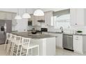 Stylish kitchen with an island and seating, white cabinets, stainless appliances, and neutral backsplash at 13644 Canyon Ridge Rd, Spring Hill, FL 34610