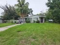 Charming single-story home featuring a cozy front porch, mature trees, and a spacious lawn at 1711 E Poinsettia Ave, Tampa, FL 33612