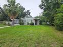 Charming single-story home featuring a cozy front porch, mature trees, and a spacious lawn at 1711 E Poinsettia Ave, Tampa, FL 33612