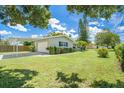 Exterior showcasing a well-maintained yard, carport, and a neatly painted home with dark shutters at 1857 N Belleair N Rd, Clearwater, FL 33764