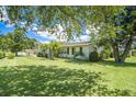 Landscaped front yard view of home with green lawn, mature trees, and vibrant blue sky at 1857 N Belleair N Rd, Clearwater, FL 33764
