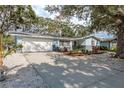 Single-story home boasting an attached two-car garage, blue and grey paint scheme, and mature landscaping at 1949 Kings Hwy, Clearwater, FL 33755
