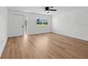 Bright living room with wood-look floors, a ceiling fan, and a large window for natural light at 20390 Lorenzo Ave, Port Charlotte, FL 33952