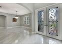 Bright foyer with decorative doors, chandelier and shiny tile flooring at 3241 Evening Breeze Loop, Wesley Chapel, FL 33544