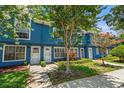 Inviting blue townhome showing the front entrance with lovely flowering trees and landscaping at 3323 Fox Hunt Dr, Palm Harbor, FL 34683