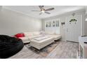 Bright living room with a large sectional sofa, modern ceiling fan, and wood-look floors at 3323 Fox Hunt Dr, Palm Harbor, FL 34683