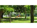 Community playground featuring slides and swings amid green lawns and mature trees at 3493 Kings Rd # 106, Palm Harbor, FL 34685