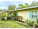 Charming single-story home displaying light blue shutters, complemented by lush, well-maintained landscaping at 3575 Lake Highland Dr, Palm Harbor, FL 34683