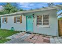 View of front exterior with bright turquoise front door, decorative shutters, and landscaped entrance at 3714 N Garrison St, Tampa, FL 33619