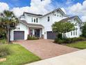 Two-story home featuring a brick driveway, well-maintained landscaping, and double garage with a basketball hoop at 4080 Bonfire Dr, Odessa, FL 33556