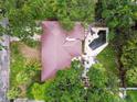 Aerial view of a home with a unique roofline, backyard pool, stone patio, and lush greenery at 5107 W Azeele St, Tampa, FL 33609