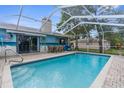 Sparkling swimming pool with screened enclosure, patio furniture, and a view of the backyard at 5112 Odin St, Spring Hill, FL 34608