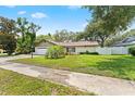 Landscaped home featuring mature trees, lush lawn, and a white garage door at 945 Winding Oaks Dr, Palm Harbor, FL 34683