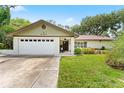 Charming one-story home featuring a well-maintained lawn, attached garage, and front porch at 945 Winding Oaks Dr, Palm Harbor, FL 34683