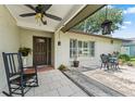 Inviting front porch with decorative plants, seating, and tile flooring at 945 Winding Oaks Dr, Palm Harbor, FL 34683