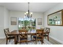 Dining room with wood table, decorative rug, chandelier and artwork beneath natural lighting at 11837 Derbyshire Dr, Tampa, FL 33626
