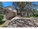 A charming two-story home features a balcony, attached garage, and shade trees in the front yard at 1310 Rustlewood Dr, Brandon, FL 33510
