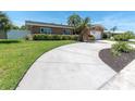 Beautiful home with lush green lawn, mature landscaping, circular driveway, and brick accent wall at 14060 102Nd Ave, Largo, FL 33774