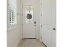 Clean entryway with a white door, light wood floors, and a decorative window at 17880 Althea Blue Pl, Lutz, FL 33558