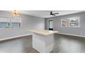 Bright living room with two windows, gray walls, wood flooring, and an island with white cabinets at 201 Bedford St # 79, Sun City Center, FL 33573