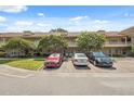 Exterior view of condo building featuring brick facade, mature trees, and parking spaces at 2192 Swedish Dr # 26, Clearwater, FL 33763