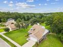 Aerial view of home with large lawn, mature trees, screened in lanai, and neighborhood pond at 422 Cypress View Dr, Oldsmar, FL 34677