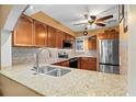 A charming kitchen with wood cabinets, stone countertops, and stainless steel appliances at 5567 Sea Forest Dr # 323, New Port Richey, FL 34652
