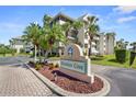 Welcoming Heather Cove condo community sign with lush landscaping featuring mature palm trees and colorful flowers at 5567 Sea Forest Dr # 323, New Port Richey, FL 34652