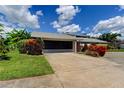 Charming house featuring well-maintained lawn and a two-car garage with dark door at 604 Knollwood Dr, Largo, FL 33770