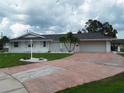 Inviting single-story home with a spacious driveway, mature palm trees, and a well-manicured front lawn at 702 Cypress Pl, Sun City Center, FL 33573