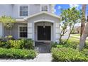 Inviting covered front porch with a stylish front door, tiled flooring, and beautifully manicured landscaping at 7515 Dragon Fly Loop, Gibsonton, FL 33534