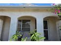 Charming home featuring an arched entryway with chairs on the porch, a security screen, and mature landscaping at 9505 Marlinton Ln, Port Richey, FL 34668